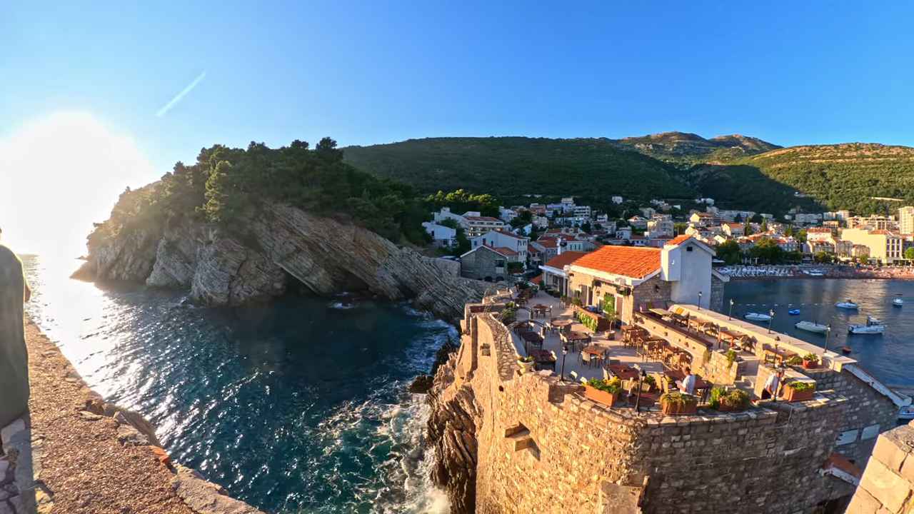 Pogled na Petrovac sa tvrđave, more, stene i obalu sa kućama pod zelenim brdima