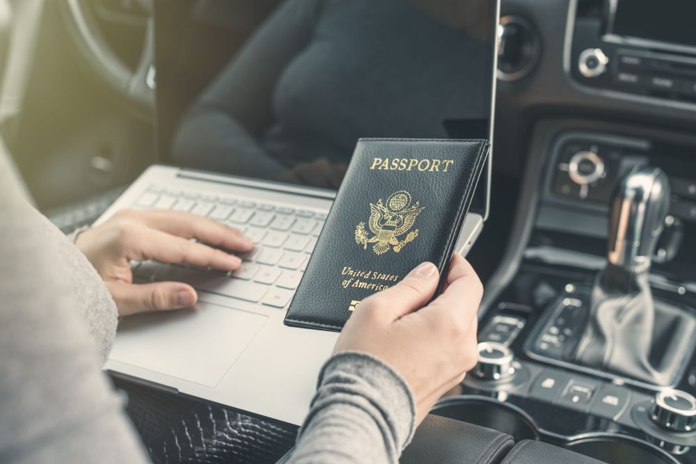 Pasoš i laptop u automobilu tokom pripreme za putovanje